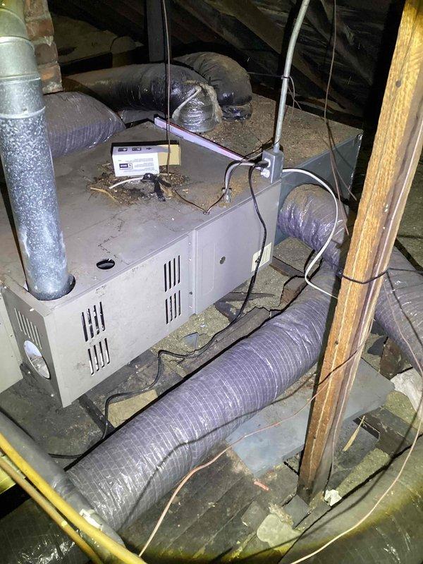 Provided comprehensive estimate for complete HVAC system replacement in attic installation, including air conditioning unit and natural gas furnace, both exceeding 15 years of age. Assessed existing equipment configuration, ductwork connections, and attic space conditions including clearances around brick chimney structure and flue pipe routing. Documented current system layout with flexible ductwork distribution, evaluated structural platform support, and identified replacement requirements for aging but currently operational heating and cooling equipment.