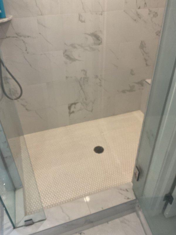 Responded to a clogged drain call in the master bathroom. Upon arrival, inspected the modern bathroom featuring a freestanding tub with floor-mounted fixtures and an adjacent walk-in shower with marble-look tile walls and hexagonal mosaic floor tile. Assessed the drainage system and successfully cleared the obstruction from the master bathroom drain, restoring proper water flow and drainage function.