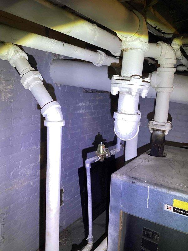 Performed estimate on hot water boiler located in basement with gas leak requiring temporary repair by utility company. Unit is over 10 years old and identified as obsolete with failing components and no replacement parts available for repair. Documented existing system including thermostat operation and plumbing configuration with PVC drainage lines and insulated supply piping. Provided replacement recommendations due to age of equipment, safety concerns from gas leak, and unavailability of serviceable parts for continued operation.