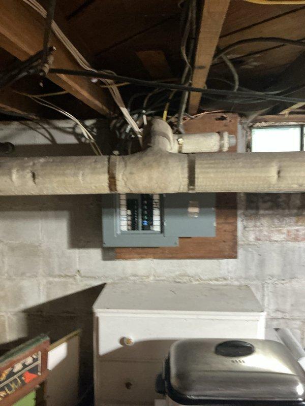 Responded to service call for electrical panel evaluation and replacement. Upon inspection, found existing panel box mounted on wooden framing in basement utility area with multiple circuit breakers showing signs of age and potential capacity limitations. Successfully replaced outdated electrical panel with new panel box, ensuring proper mounting to structural framing and maintaining code-compliant clearances. Reorganized and secured all incoming electrical cables, including black, white, and yellow conductors, ensuring proper connections to new breaker configuration. Verified all circuits were properly labeled and functioning, with adequate capacity for current and future electrical loads throughout the residence.