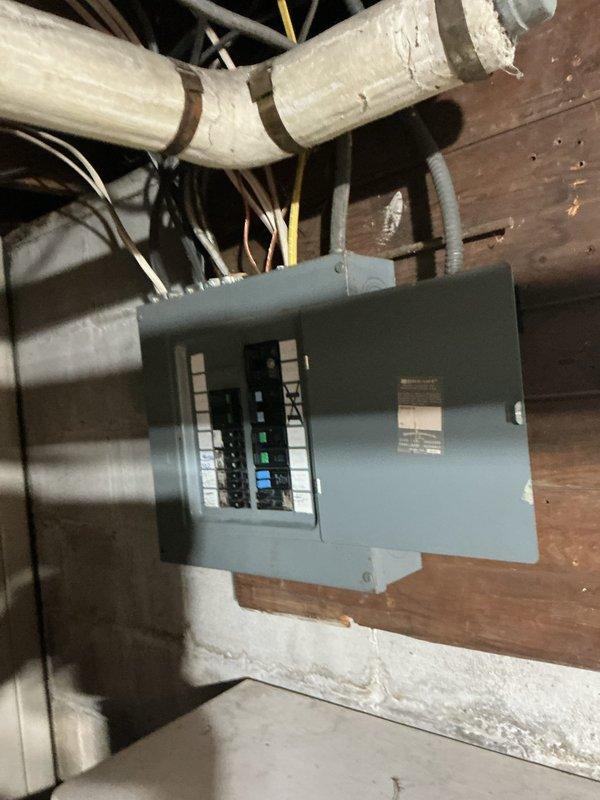 Responded to service call for electrical panel evaluation and replacement. Upon inspection, found existing panel box mounted on wooden framing in basement utility area with multiple circuit breakers showing signs of age and potential capacity limitations. Successfully replaced outdated electrical panel with new panel box, ensuring proper mounting to structural framing and maintaining code-compliant clearances. Reorganized and secured all incoming electrical cables, including black, white, and yellow conductors, ensuring proper connections to new breaker configuration. Verified all circuits were properly labeled and functioning, with adequate capacity for current and future electrical loads throughout the residence.