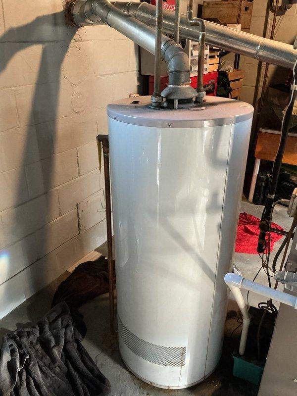 Responded to hot water heater leak in basement utility room. Upon inspection, identified loose connection at hot water outlet piping causing active leak. Shut off water supply to unit and drained necessary water from system. Disconnected and properly reconnected hot water piping connections at top of heater, ensuring proper thread seal and torque specifications. Verified pressure relief valve operation and checked all associated plumbing connections for integrity. Restored water supply, filled tank, and tested system under pressure to confirm leak was resolved with no further drips or moisture detected. Cleaned work area and removed water-damaged materials from floor near unit base.