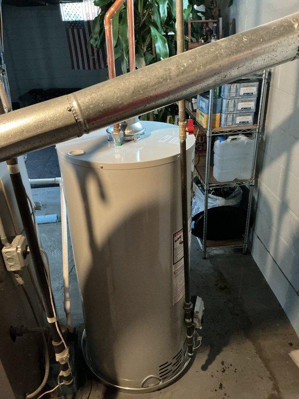 Responded to hot water heater leak in basement utility room. Upon inspection, identified loose connection at hot water outlet piping causing active leak. Shut off water supply to unit and drained necessary water from system. Disconnected and properly reconnected hot water piping connections at top of heater, ensuring proper thread seal and torque specifications. Verified pressure relief valve operation and checked all associated plumbing connections for integrity. Restored water supply, filled tank, and tested system under pressure to confirm leak was resolved with no further drips or moisture detected. Cleaned work area and removed water-damaged materials from floor near unit base.