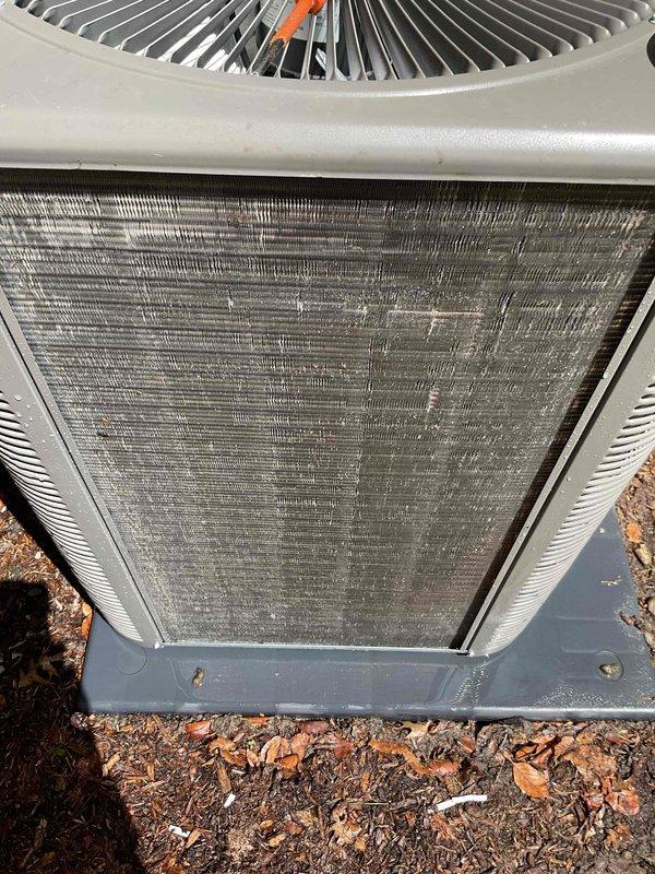 Performed comprehensive cooling system inspection on a 2-year-old residential air conditioning unit as part of annual maintenance plan renewal. Outdoor condenser unit located on concrete pad adjacent to building showed significant accumulation of dirt, dust, and debris in condenser coil fins. Conducted thorough visual assessment of equipment including fan assembly, electrical connections, and overall system operation. Air handler/coil located in basement was included in inspection protocol. Unit confirmed operational at time of service with no immediate mechanical failures noted. Documented equipment condition through photographic evidence showing exterior casing, fan grille assembly, and condenser coil contamination levels. Condenser fins displayed substantial clogging requiring attention to maintain optimal heat transfer efficiency and system performance. Electrical disconnect box and conduit connections inspected and found secure. Concrete mounting pad stable with proper equipment p