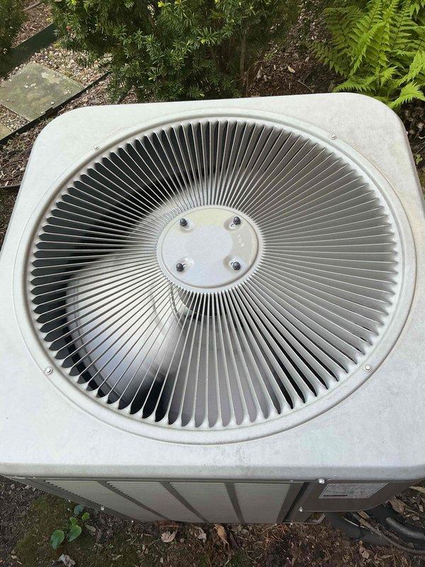 Completed comprehensive Gold AC inspection on single residential cooling system with air handler located in basement. Performed thorough examination of outdoor condenser unit, confirming proper fan assembly operation, intact coil fins, and adequate clearance from surrounding landscaping and debris. System operational with no immediate service needs identified; documented equipment condition with photographic records showing unit in functional condition with minor weathering consistent with outdoor exposure.