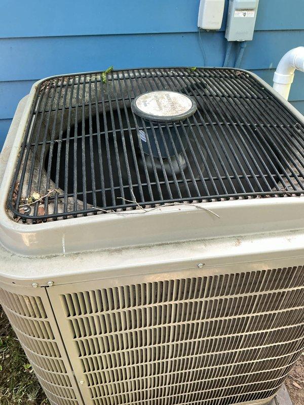 Completed comprehensive Gold AC Inspection on a 4-year-old residential split system with two units and air handler located in basement. Performed full system evaluation of outdoor condenser unit including visual inspection of cabinet condition, refrigerant line insulation, electrical disconnect, and fan grille assembly. Noted debris accumulation on top grille and surrounding area with vegetation growth near unit base. Verified equipment operational status, documented system configuration, and captured photographic records of exterior condenser placement and condition. Recommended routine debris removal from top grille to maintain optimal airflow and system efficiency.
