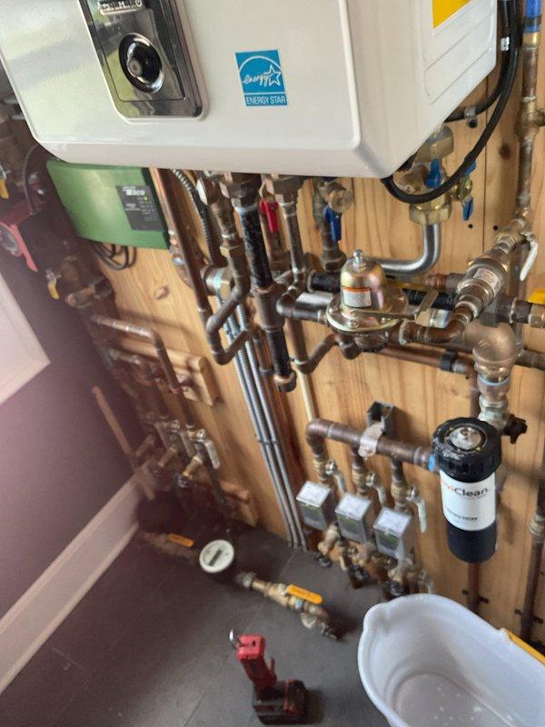 Responded to service call for tankless water heater not producing hot water. Upon arrival, inspected Navien NCB-A0801/26U combination unit and associated plumbing system. Evaluated control panel settings, verified gas supply, checked water flow rates through inlet valves, and examined venting system. Tested multiple hot water fixtures throughout property to confirm lack of hot water production. Inspected complex manifold configuration including ball valves, brass fittings, water filtration system, and copper supply lines for proper operation. Documented existing installation with photographs showing Energy Star rated unit, plumbing connections, and system components for service records.