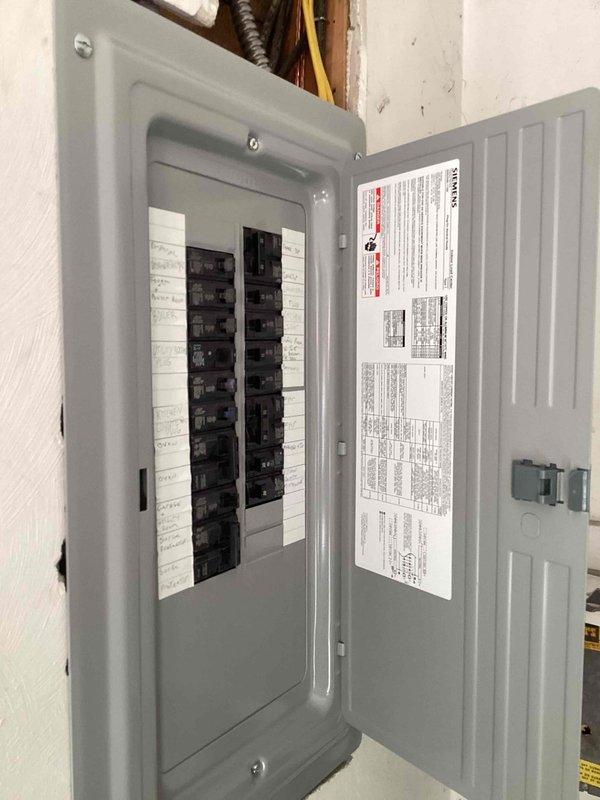 Completed HVAC estimate for new mini split installation in residential property currently heated by boiler with no existing ductwork. Evaluated electrical panel capacity and circuit availability to support new mini split system. Assessed den area for indoor air handler placement and documented proposed installation location on wall above existing furniture. Photographed electrical infrastructure and proposed installation area to develop equipment specifications and installation plan.