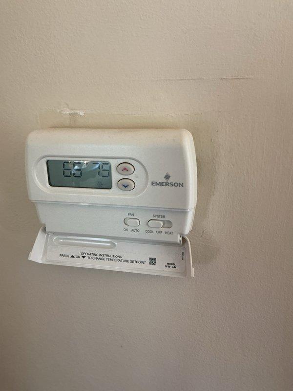 Completed comprehensive Gold AC inspection on residential single-unit system installed in 2018 with air handler located in basement. Performed full system evaluation including thermostat operation verification, temperature differential measurements, and visual inspection of all accessible components. System found operating within normal parameters with Emerson digital thermostat displaying proper temperature readings and responsive controls. Documented equipment condition through photographic records showing properly functioning thermostat and basement mechanical room layout. All safety checks passed and unit confirmed operational at time of service.