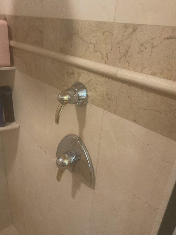 Responded to water leak in primary bathroom. Upon inspection, identified leak originating from shower valve assembly. Examined chrome shower fixtures including diverter valve and mixing valve mounted on marble-look tile wall. Tightened valve connections and replaced worn internal seals and O-rings on both the upper diverter valve and lower mixing valve to eliminate water intrusion. Tested system under full pressure to verify leak was resolved and confirmed proper operation of all shower controls. No further seepage detected upon completion.