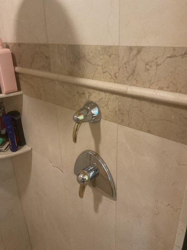 Responded to water leak in primary bathroom. Upon inspection, identified leak originating from shower valve assembly. Examined chrome shower fixtures including diverter valve and mixing valve mounted on marble-look tile wall. Tightened valve connections and replaced worn internal seals and O-rings on both the upper diverter valve and lower mixing valve to eliminate water intrusion. Tested system under full pressure to verify leak was resolved and confirmed proper operation of all shower controls. No further seepage detected upon completion.