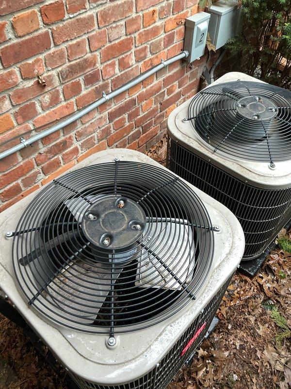 Completed Gold AC Inspection on single-unit residential HVAC system with 2015 equipment. Performed comprehensive maintenance evaluation of two outdoor condenser units located at ground level against building exterior and air handler/coil assembly located in basement. Inspected fan assemblies, protective grilles, and motor hubs on both condenser units, noting normal wear consistent with age and outdoor exposure. Verified operational status of equipment, confirmed proper electrical connections and conduit mounting, and assessed overall system condition. All components functioning as designed with weathering appropriate for unit age.