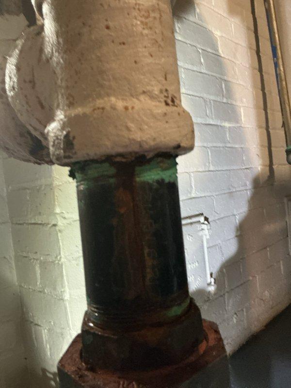 Responded to service call for boiler leaking onto floor from recent installation completed in March. Upon inspection, identified active leak at pipe connection point with visible water damage and significant corrosion present on brass fitting and galvanized piping. Photographic documentation captured corroded brass fitting with orange-brown oxidation staining at connection interface, green gasket seal, and deteriorated metal pipe showing heavy rust, green patina, and surface corrosion throughout vertical run. Confirmed leaking components were part of original installation work, requiring recall evaluation and repair of faulty plumbing connections.
