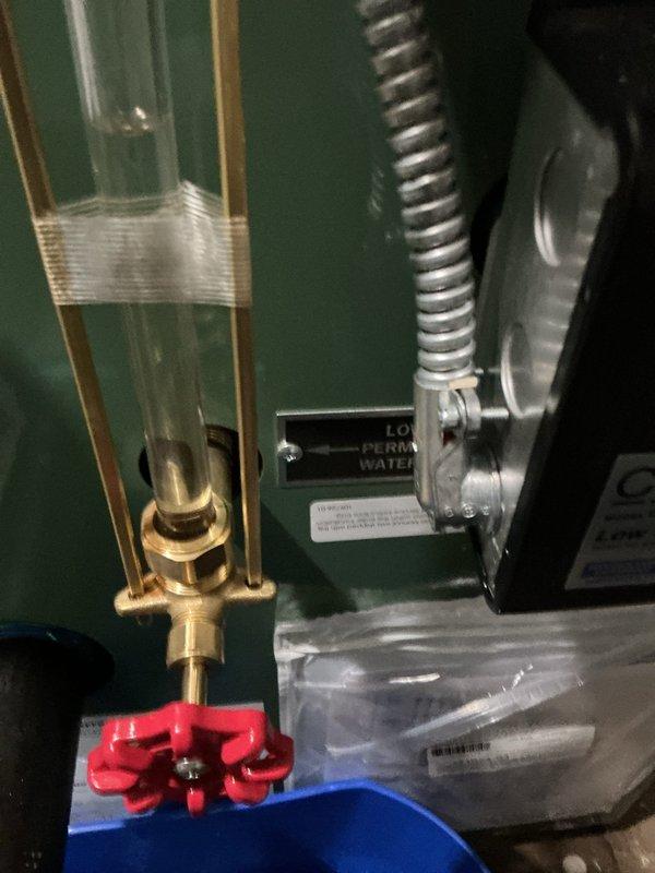 Responded to callback for recently installed steam boiler reported to be leaking. Upon arrival, performed thorough visual inspection of boiler unit, sight glass assembly, brass valve connections, and all associated piping and fittings. Examined sight tube with brass fittings and red valve mounting bracket for signs of moisture or active leaks. Inspected all connection points on the green boiler casing, including the low water cutoff area and valve assembly extensions. Checked flexible corrugated piping and metal ductwork connections for proper sealing. Documented boiler condition with photographs showing sight glass, valve assembly, mounting hardware, and surrounding components. No active leaking observed during inspection period. All brass fittings, valve connections, and sight glass assembly appeared secure and properly installed. System pressure and water level within normal operating parameters at time of service call.