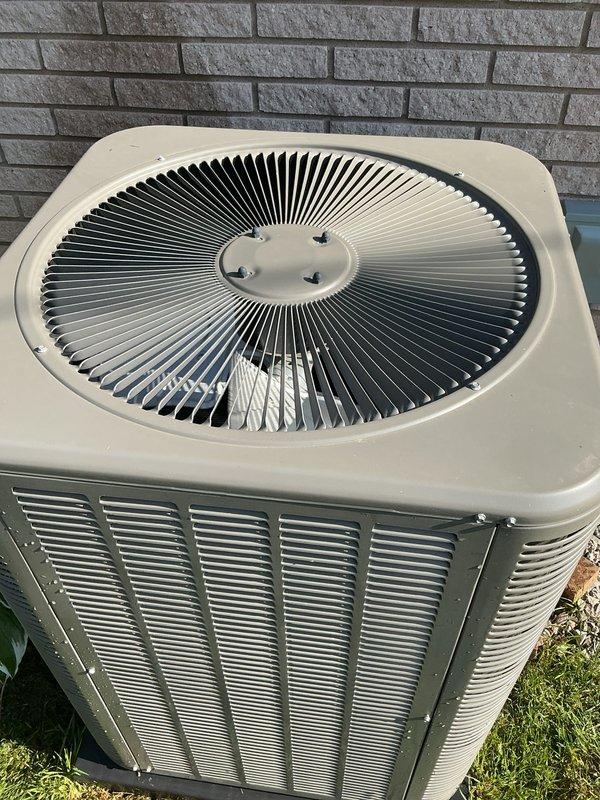 Completed comprehensive Gold AC inspection on 2-year-old residential air conditioning system with air handler/coil located in basement. Performed thorough examination of outdoor condenser unit, verifying proper operation of fan assembly, inspecting condenser coils through louvered panels, and confirming unit is mounted securely on concrete pad. Advised customer that area surrounding condenser should be kept clear of debris and animal waste for optimal performance and airflow. Verified system operational status and documented equipment condition through photographic records showing well-maintained exterior components with no visible damage or excessive wear on accessible surfaces.