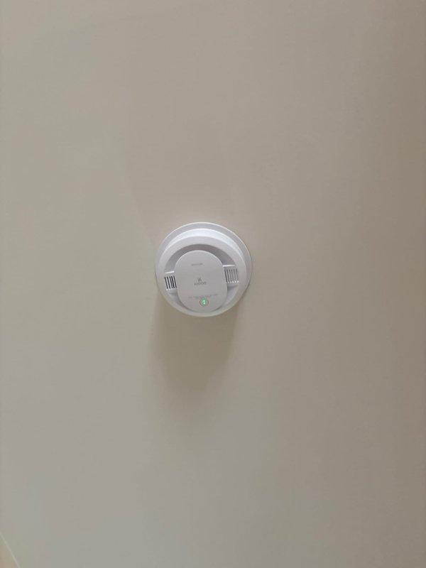 Removed existing smoke detector from ceiling and installed new replacement unit in attic space. Verified proper mounting to structural framework, tested functionality including LED indicator operation, and confirmed detector was securely fastened to ceiling surface per manufacturer specifications.