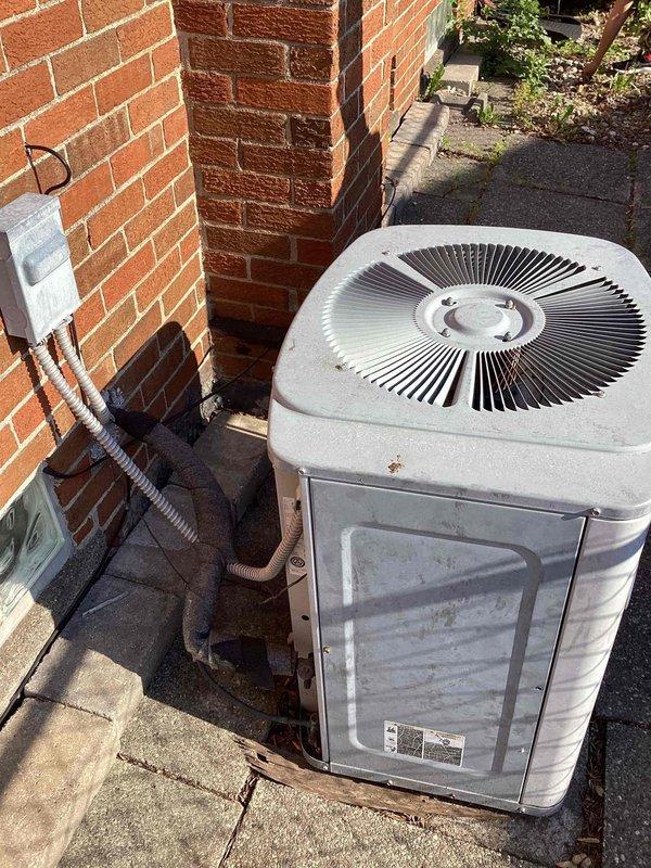Conducted comprehensive assessment of existing heating and cooling system for small residential property under 1500 square feet with basement-mounted equipment and natural gas energy source. Evaluated outdoor air conditioning condenser unit showing signs of age and wear, along with associated refrigerant lines and controls mounted on exterior brick wall. Inspected basement mechanical room where severe ice accumulation was discovered on refrigerant lines, indicating potential refrigerant leak, insufficient airflow, or system malfunction requiring complete system replacement rather than repair.