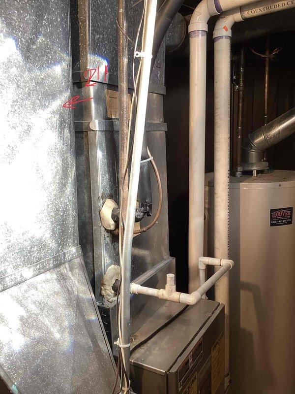 Conducted comprehensive assessment of existing heating and cooling system for small residential property under 1500 square feet with basement-mounted equipment and natural gas energy source. Evaluated outdoor air conditioning condenser unit showing signs of age and wear, along with associated refrigerant lines and controls mounted on exterior brick wall. Inspected basement mechanical room where severe ice accumulation was discovered on refrigerant lines, indicating potential refrigerant leak, insufficient airflow, or system malfunction requiring complete system replacement rather than repair.