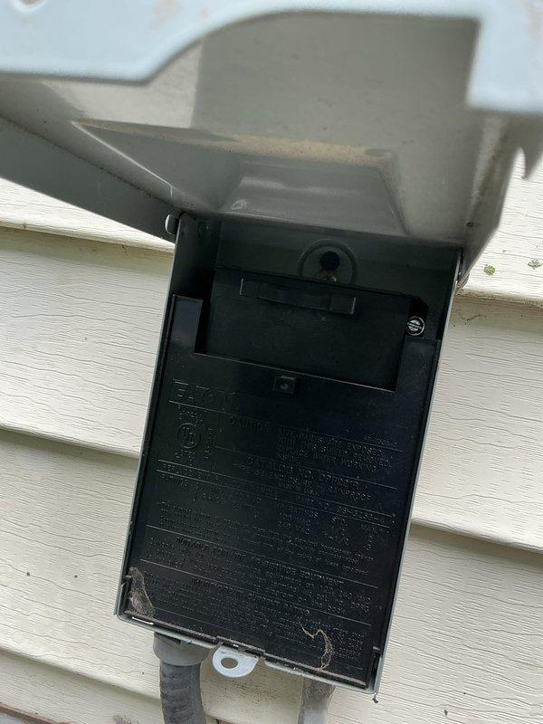 Completed Gold AC Inspection on a 7-year-old single air conditioning system with air handler located in basement. Verified equipment operational status with homeowner present. Performed comprehensive visual inspection of outdoor condenser unit, confirming proper installation on composite pad with adequate clearance from foundation. Inspected exterior electrical disconnect box mounted on vinyl siding, verified weatherproof cover functionality and conduit connections. Documented equipment condition through photographic records showing condenser unit positioning, fan guard integrity, and electrical components. All systems confirmed operational at time of inspection.