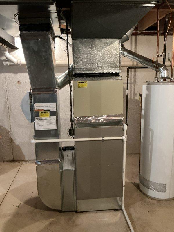 Provided estimate for complete air conditioning system replacement including evaporator coil located in basement. Existing 10+ year old unit is non-operational. Assessment included inspection of current natural gas furnace installation, basement-mounted evaporator coil, and existing ductwork distribution system throughout the property to determine compatibility and requirements for new equipment installation.