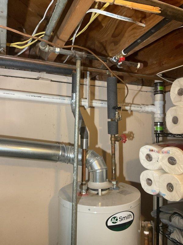 Responded to report of possible water heater leak with rust-colored water damage, mineral deposits in mechanical room, and cloudy hot water throughout residence. Upon inspection of 75-year-old home's utility area, examined AO Smith water heater, surrounding copper and PVC plumbing lines, and associated mechanical systems. Documented existing conditions including water heater installation, piping configuration, HVAC ductwork, and Honeywell humidifier system. Photographed mechanical room showing water heater, multi-material piping system with brass valves, foam pipe insulation, and overhead drain/waste/vent lines to establish baseline conditions for leak source identification and recommend appropriate repairs.
