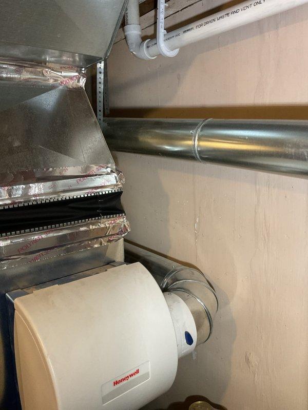 Responded to report of possible water heater leak with rust-colored water damage, mineral deposits in mechanical room, and cloudy hot water throughout residence. Upon inspection of 75-year-old home's utility area, examined AO Smith water heater, surrounding copper and PVC plumbing lines, and associated mechanical systems. Documented existing conditions including water heater installation, piping configuration, HVAC ductwork, and Honeywell humidifier system. Photographed mechanical room showing water heater, multi-material piping system with brass valves, foam pipe insulation, and overhead drain/waste/vent lines to establish baseline conditions for leak source identification and recommend appropriate repairs.