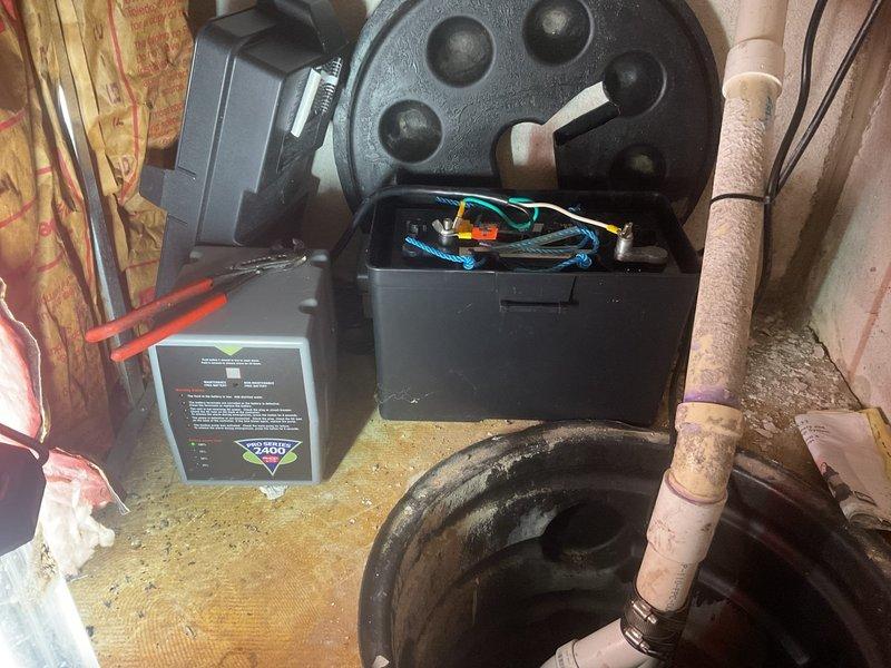 Serviced Pro Series 1/3 HP sump pump system experiencing indicator light issues with red and green lights activating. Inspected pump housing, control unit, and electrical connections in basement utility area. Examined wiring bundle containing multiple colored conductors within pump basin housing. Verified proper operation of float switch mechanism and checked control box functionality. Assessed discharge piping system including copper lines with insulation. Tested pump motor operation and confirmed system cycling properly after service intervention.