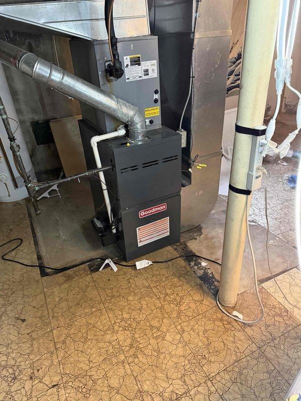 Responded to no-cooling complaint on 7-year-old Goodman air conditioning system. Upon arrival, performed diagnostic inspection of outdoor condensing unit and indoor air handler. Outdoor unit showed signs of environmental exposure with oxidized copper refrigerant lines and accumulated debris around service valves. Conducted system evaluation including electrical connections, refrigerant pressures, and operational testing. Documented equipment condition with photos showing outdoor unit components and indoor furnace installation. System assessed and customer advised of findings.