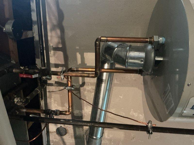 Completed comprehensive Gold AC Inspection on a 10+ year old single-unit air conditioning system with air handler located in basement. Performed thorough examination of outdoor condenser unit, refrigerant lines, electrical connections, and indoor mechanical components including pump assembly and copper piping configuration. System confirmed operational at time of inspection with all components functioning properly and documented with photographic evidence of equipment condition.
