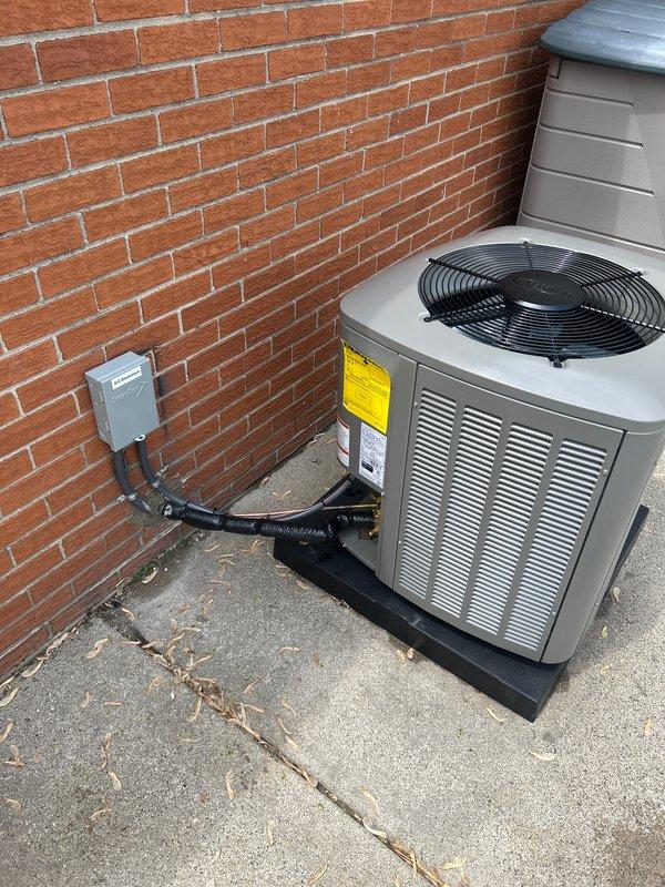 Completed installation of 2-ton air conditioning system with evaporator coil at rear of residence. Unit was positioned on concrete pad against brick wall with proper clearances maintained. Connected electrical service via disconnect box with appropriate conduit routing, installed refrigerant line set, and reconnected thermostat for system operation. Mechanical, electrical, and air conditioning permits were requested and system was tested for proper operation upon completion.