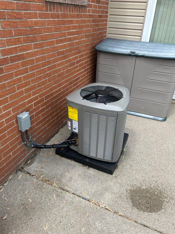 Completed installation of 2-ton air conditioning system with evaporator coil at rear of residence. Unit was positioned on concrete pad against brick wall with proper clearances maintained. Connected electrical service via disconnect box with appropriate conduit routing, installed refrigerant line set, and reconnected thermostat for system operation. Mechanical, electrical, and air conditioning permits were requested and system was tested for proper operation upon completion.