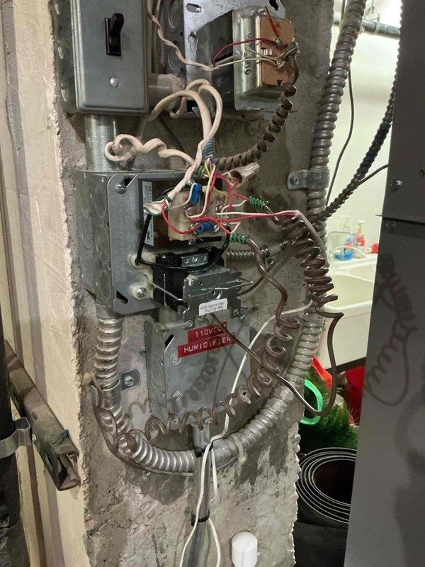 Responded to no cooling call for 3-year-old air handler system located in basement. Upon arrival, confirmed neither the air handler blower nor outdoor condensing unit were operating, though power was present at the equipment. Performed diagnostic evaluation of electrical control system and humidifier integration. Inspected control relay/transformer assembly and associated wiring connections within air handler control compartment. Examined capacitor previously replaced one year prior. Documented existing electrical configuration including humidifier control wiring, relay connections, and power distribution components for system troubleshooting and repair recommendations.
