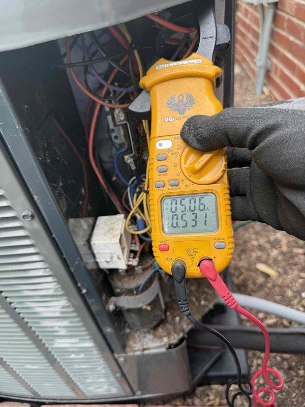 Responded to service call for 16-year-old air conditioning system experiencing inadequate cooling performance. Performed comprehensive diagnostic inspection of outdoor condensing unit with focus on compressor operation and electrical components. Utilized digital clamp meter to measure amperage draw and verify electrical readings at compressor terminals and contactor connections. Accessed unit's electrical compartment to test voltage and current flow through system components. Inspected condenser coil condition, fan motor operation, and overall unit integrity. Documented findings with photographic evidence of electrical measurements and unit condition for customer records and future reference.