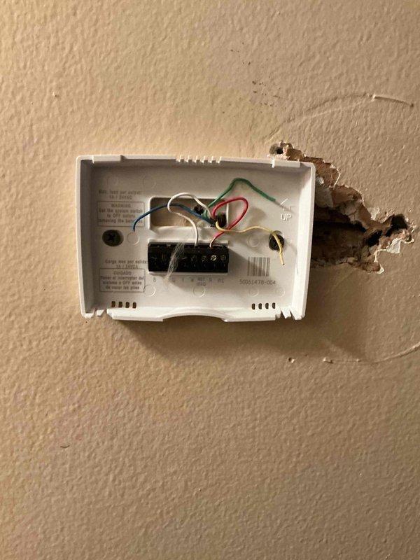 # HVAC Service Completed

Responded to no-cooling complaint on 2-year-old residential air conditioning system. Upon arrival, performed diagnostic assessment of AC unit located adjacent to furnace in basement utility area. 

Inspected thermostat wiring and found improper connections at wall-mounted control. Removed thermostat cover to access terminal block and identified multiple wire connection issues affecting system operation. Corrected wiring configuration at thermostat, ensuring proper connections for R, C, Y, G, and W terminals to restore communication between thermostat and outdoor condensing unit.

Verified air filter condition in supply ductwork—found 16x filter in acceptable condition with no significant blockage affecting airflow. Inspected ductwork connections and confirmed proper sealing at filter housing.

Cycled system through cooling mode to verify proper operation. Confirmed compressor engagement, indoor blower activation, and thermostat responding correctly to temperat
