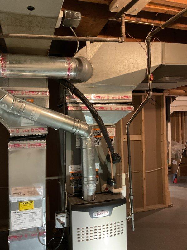 Completed full HVAC system installation including 90,000 BTU high-efficiency furnace, 2.5-ton air conditioning unit, programmable thermostat, and humidifier in unfinished basement location. Installed new metallic ductwork with insulation wrapping, connected copper refrigerant lines, and ran PVC venting for condensate drainage. Mounted furnace on concrete floor against block wall foundation with proper clearances. Ran black electrical conduit and wiring for power connections. Installed supply and return air plenums with pink foam insulation board. Connected all ductwork to existing trunk lines with 600 CFM airflow capacity. Installed condensate pump for drainage management and performed system flush. Reconnected existing electrical circuits as required. Verified proper refrigerant charge and system pressures. Tested all safety controls, ignition sequence, and airflow distribution. System startup completed with all equipment operating within manufacturer specifications. Mechanical and el