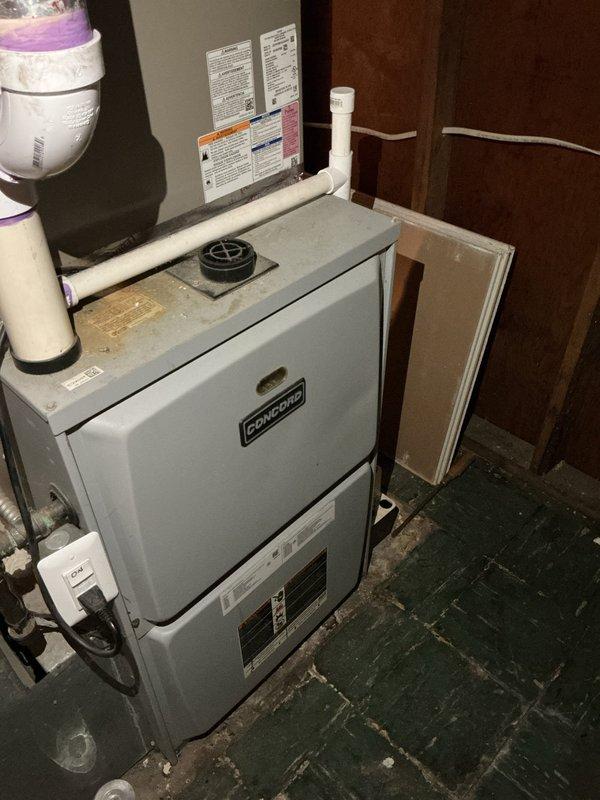 Responded to service call for air conditioning system not cooling adequately despite unit running and producing cold air. Upon arrival, found AC unit operational with fan running and evaporator coil sweating, indicating refrigerant flow. Conducted comprehensive system evaluation including inspection of indoor furnace unit and associated components in mechanical room. Examined Concord furnace installation, PVC condensate drainage lines, copper refrigerant lines, and electrical connections. Assessed airflow through system and verified proper operation of all mechanical components. Inspected evaporator coil condition and confirmed condensation present but noted insufficient cooling performance to living space. Evaluated ductwork accessibility and system configuration. Documented equipment condition through photographs showing installation layout, piping configuration, and component placement. Customer advised of findings and provided recommendations for resolution of inadequate cooling is
