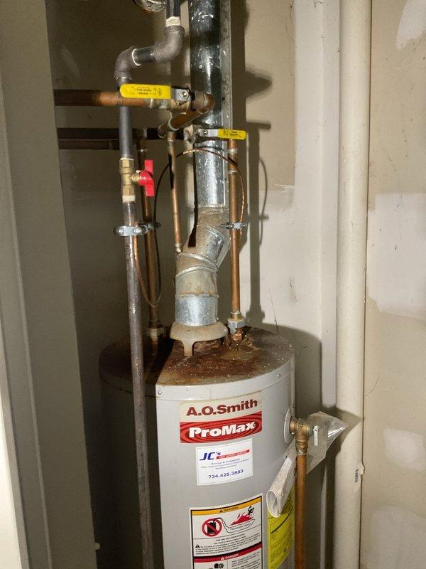 Completed installation of 40-gallon A.O. Smith ProMax residential water heater in basement utility area. Reconnected all plumbing connections including hot and cold water supply lines with copper and galvanized steel piping, installed pressure relief valve assembly with proper discharge piping, and integrated yellow-handled shut-off valves and red-handled isolation valves for system control. Verified all brass fittings and connections were secure, tested system operation, and confirmed no leaks at connection points. Unit installed on concrete floor with proper clearances maintained for ventilation and service access.