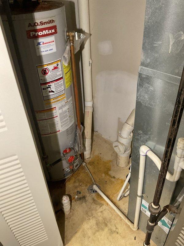 Completed installation of 40-gallon A.O. Smith ProMax residential water heater in basement utility area. Reconnected all plumbing connections including hot and cold water supply lines with copper and galvanized steel piping, installed pressure relief valve assembly with proper discharge piping, and integrated yellow-handled shut-off valves and red-handled isolation valves for system control. Verified all brass fittings and connections were secure, tested system operation, and confirmed no leaks at connection points. Unit installed on concrete floor with proper clearances maintained for ventilation and service access.