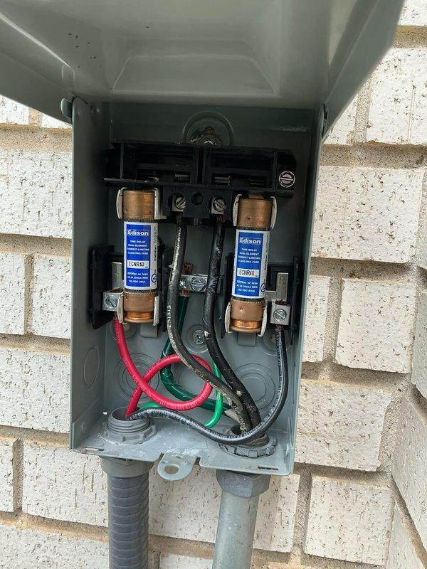 Completed comprehensive Gold AC Inspection on residential air conditioning system with unit under 10 years old and evaporator coil located in basement. Inspected outdoor disconnect box containing Edison cartridge-style fuses, verified proper electrical connections including red, black, and green wiring through conduit fittings, and confirmed fuse holder assembly operational. Evaluated Aprilaire humidifier unit installation and associated ductwork connections. All components photographed and documented for service records.