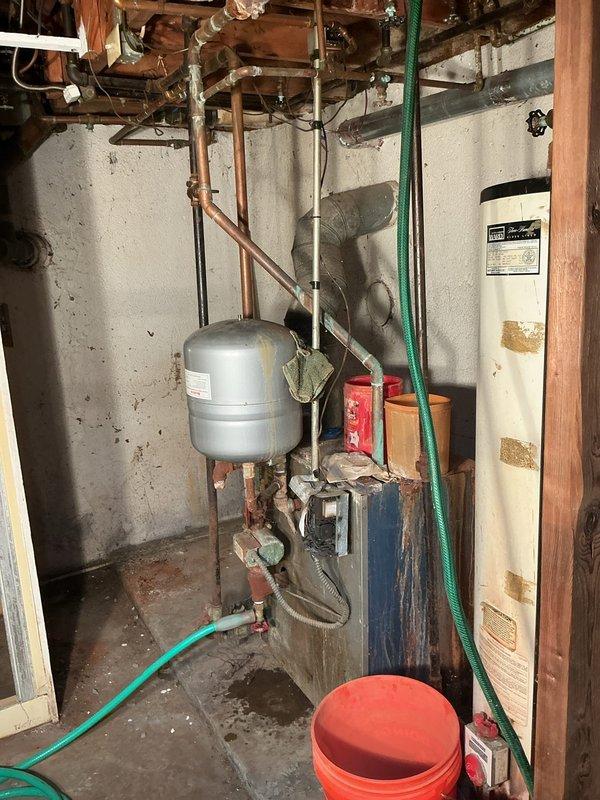 Responded to request for boiler disconnect on approximately 30-year-old unit in basement that was already shut off and locked in place. Coordinated arrival time with property owner as requested. Upon arrival, documented existing conditions of aged heating system including expansion tank, circulator pump, and associated copper piping showing normal wear and corrosion consistent with age. Verified boiler was secured and all connections were in safe condition for disconnect process. Completed photographic documentation of equipment and surrounding utility area prior to disconnect work.