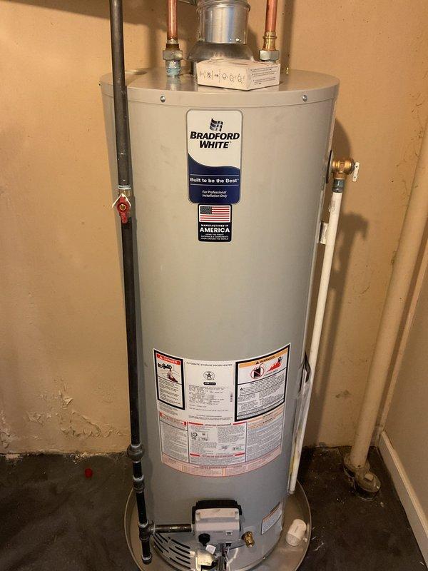Completed installation of a 40-gallon Bradford White tanked water heater in basement utility area. Established all necessary plumbing connections including copper supply lines with brass fittings, installed expansion tank, configured proper venting with flue pipe and shutoff valve, and verified all code-compliant connections for safe operation.