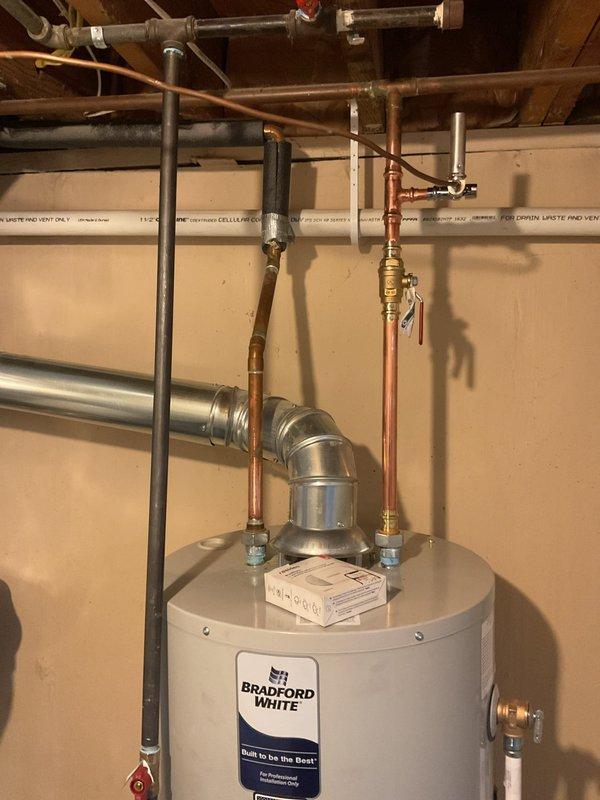 Completed installation of a 40-gallon Bradford White tanked water heater in basement utility area. Established all necessary plumbing connections including copper supply lines with brass fittings, installed expansion tank, configured proper venting with flue pipe and shutoff valve, and verified all code-compliant connections for safe operation.