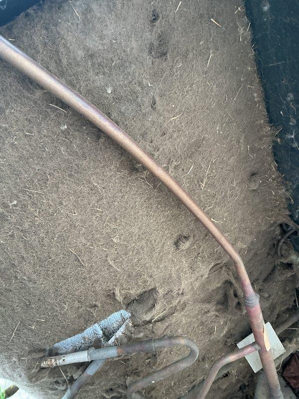 Responded to service call for air conditioning system experiencing intermittent operation. Upon arrival, located outdoor condenser unit at side of residence with visible accumulation of dirt, debris, and pollen on housing and coil surfaces. Inspected refrigerant lines and noted weathered copper piping with age-related tarnishing. Condenser unit displayed moderate weathering consistent with extended outdoor exposure and lack of recent maintenance.

Performed visual assessment of condenser coil fins, which showed significant dust and grime buildup restricting airflow. Documented current condition of unit including debris accumulation on fan grille and housing surfaces. Unit positioned on composite pad with adequate clearance from structure. Electrical conduit and refrigerant lines inspected for obvious damage or deterioration. Recommended thorough coil cleaning and system evaluation to address intermittent operation issue and restore proper airflow efficiency.