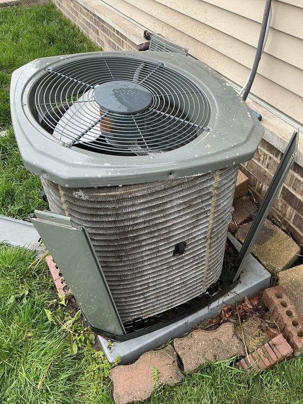Responded to service call for air conditioning system experiencing intermittent operation. Upon arrival, located outdoor condenser unit at side of residence with visible accumulation of dirt, debris, and pollen on housing and coil surfaces. Inspected refrigerant lines and noted weathered copper piping with age-related tarnishing. Condenser unit displayed moderate weathering consistent with extended outdoor exposure and lack of recent maintenance.

Performed visual assessment of condenser coil fins, which showed significant dust and grime buildup restricting airflow. Documented current condition of unit including debris accumulation on fan grille and housing surfaces. Unit positioned on composite pad with adequate clearance from structure. Electrical conduit and refrigerant lines inspected for obvious damage or deterioration. Recommended thorough coil cleaning and system evaluation to address intermittent operation issue and restore proper airflow efficiency.