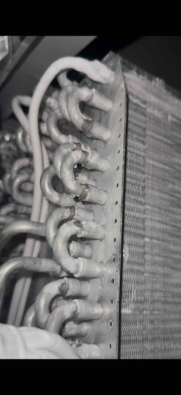 Responded to service call for Lennox 13ACXN060-230 central air conditioning system installed in April 2018 with inadequate cooling performance. Upon inspection, discovered severely corroded evaporator coil with extensive oxidation on copper refrigerant tubes and U-bend connections. The deteriorated condition of the coil assembly was determined to be the primary cause of reduced cooling capacity. Documented existing equipment condition including furnace, ductwork, and PVC venting system. Evaporator coil replacement required and has been ordered under purchase order 1324783-001 for installation to restore proper system operation and cooling efficiency.