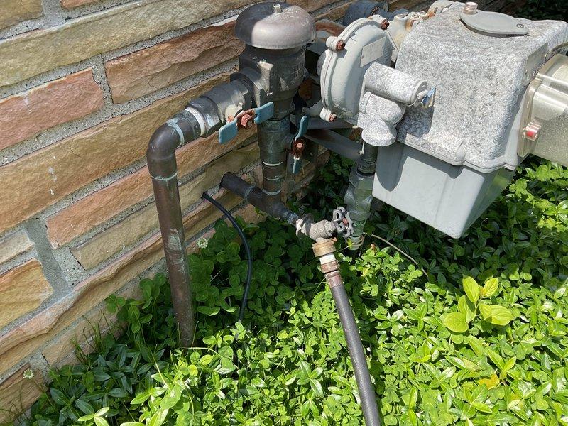 # Outdoor Spigot Replacement and Code Compliance Upgrade

Responded to service request for replacement of two exterior hose bibs requiring code compliance updates at front and rear yard locations. Upon arrival, assessed existing outdoor plumbing installations mounted on building exterior against brick and horizontal siding.

## Work Performed

**Front Yard Spigot Assembly:**
Removed existing weathered outdoor faucet system showing significant corrosion and aging. Existing configuration included deteriorated copper piping with blue-green patina buildup and heavily oxidized brass valve components with brown rust accumulation. Disconnected obsolete plumbing assembly including corroded galvanized fittings and compromised connection points. 

Installed new code-compliant frost-proof sillcock with proper pitch for drainage. Configured new copper supply line connections with lead-free solder joints. Integrated backflow prevention device per current plumbing code requirements. Secured all pipi