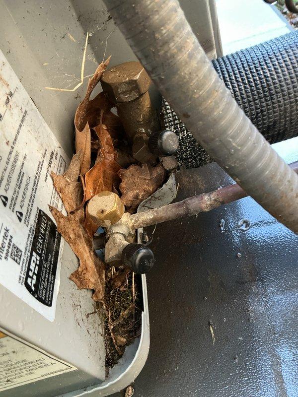 Performed leak search and tune-up on 4-year-old residential HVAC system with air handler located in basement. Replaced metering device gasket as requested. Inspected outdoor unit electrical disconnect box and refrigerant line connections, finding all components properly secured and in good working condition. Removed accumulated organic debris including leaves, twigs, and dirt from condensate drain pan. Inspected drain pan components and noted corrosion on some fasteners. Verified system operational status with all equipment functioning properly at time of service.