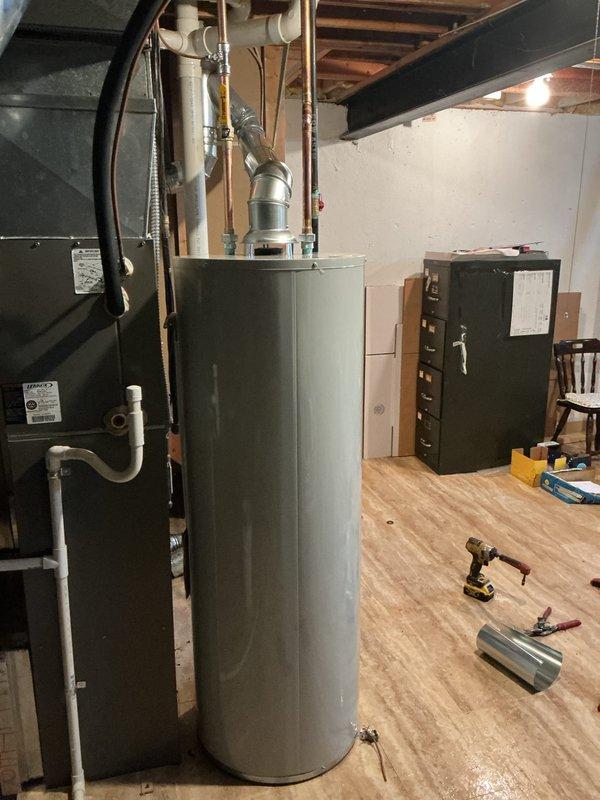 Replaced failed water heater with new 40-gallon Bradford White natural draft unit in basement utility area. Removed existing water heater, installed new unit with proper copper supply and discharge piping connections, installed code-compliant temperature and pressure relief valve with discharge line, and connected natural gas supply with flexible connector. Verified proper venting configuration, tested all connections for leaks, filled tank, ignited pilot light, and confirmed unit operational. Inspected 11-year-old furnace as requested and addressed water accumulation issue on basement floor in vicinity of mechanical equipment.