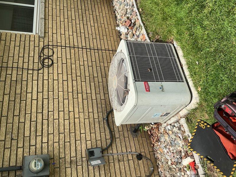 Completed comprehensive air conditioning inspection and tune-up on 20-year-old residential cooling system with outdoor condenser unit located in backyard on wooden deck and indoor components in basement. Performed full system evaluation including inspection of electrical connections at junction box, assessed condenser unit operation and heat exchanger condition, verified proper electrical supply at disconnect box, and documented equipment condition with focus on aging components showing weathering and oxidation on exterior panels and electrical housing. All accessible components inspected and system operational at time of service completion.