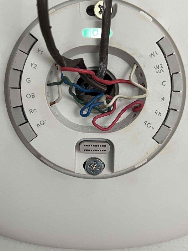 Responded to service call for thermostat not activating air conditioning system while furnace operation remained functional. Upon inspection, found thermostat wiring configuration with multiple conductors present including Y1, Y2, G, OB, RC, W1, W2 AUX, C, and Rh terminals. Verified proper wire connections at thermostat base plate and traced wiring through attic space to air handler location. Identified cooling call circuit issue preventing compressor engagement. Corrected wiring connections at thermostat terminal block to restore proper communication between thermostat and 10+ year old air conditioning unit. Tested system operation through complete cooling cycle to confirm proper compressor startup and verified furnace heating function remained intact. System now operating correctly in both heating and cooling modes.